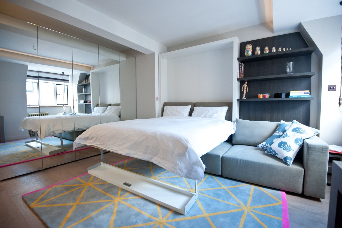 Open-plan bedroom and living space with mirrored wardrobes