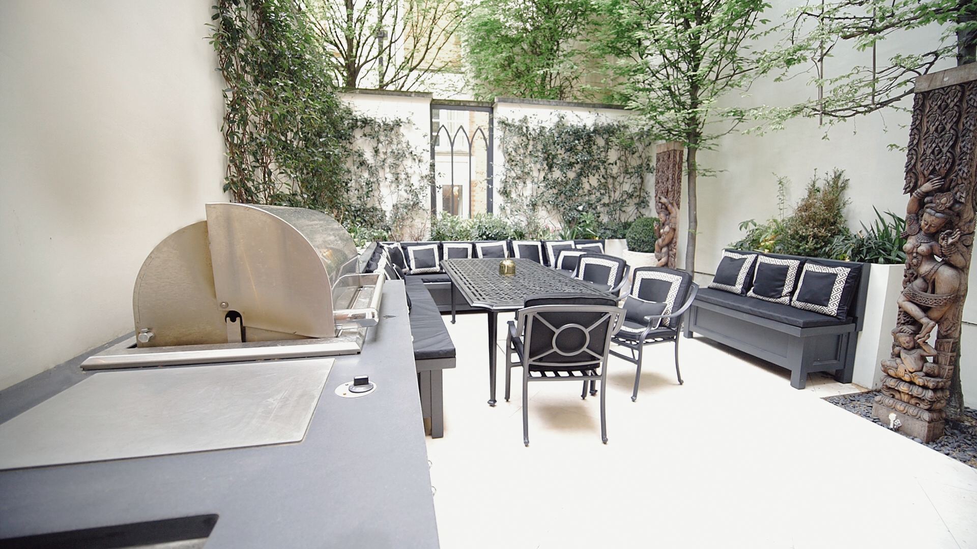 Walled courtyard garden with built-in grill, banquette seating and stone paving