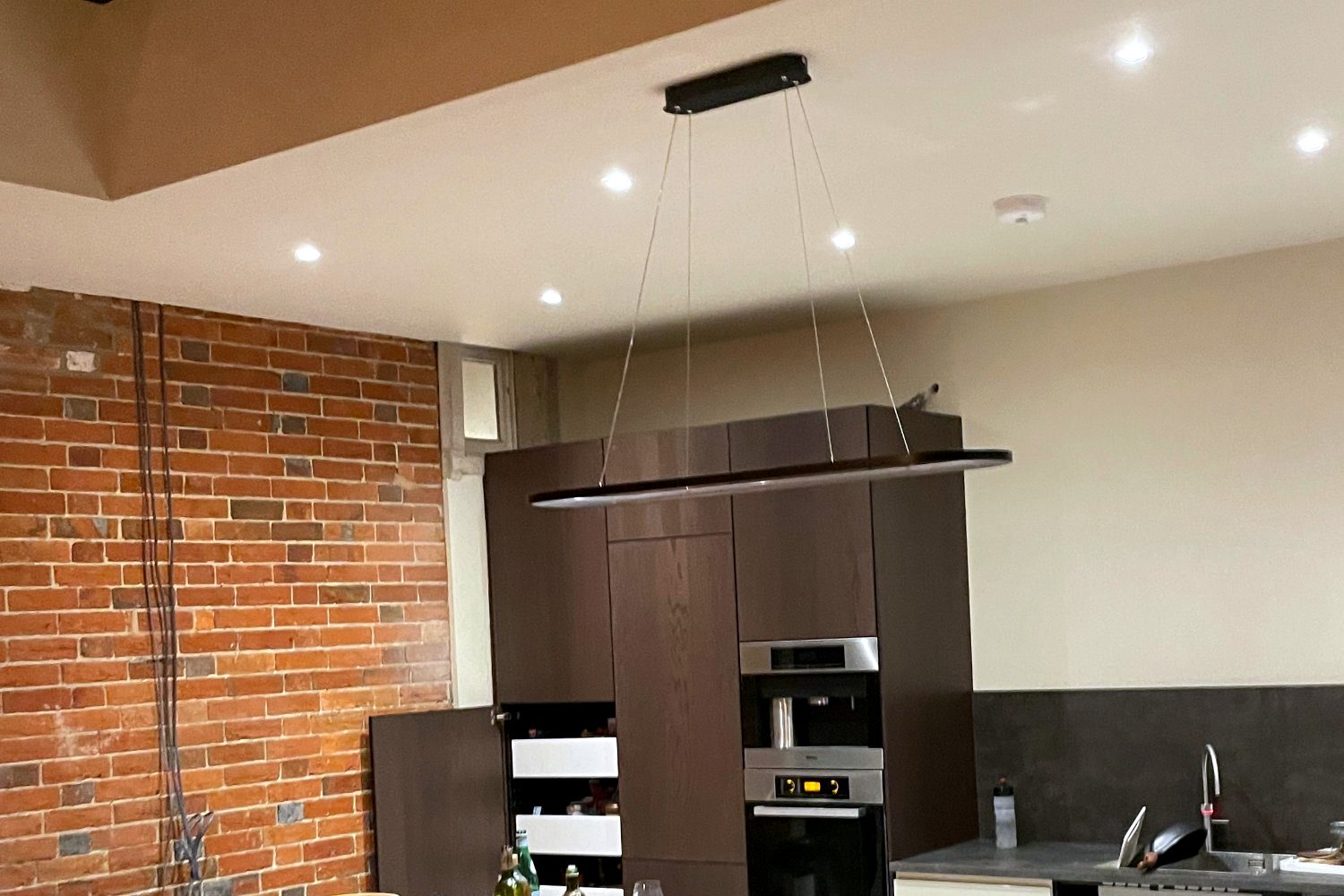 Kitchen extension with island, round oak breakfast table, roof lantern and exposed brick wall